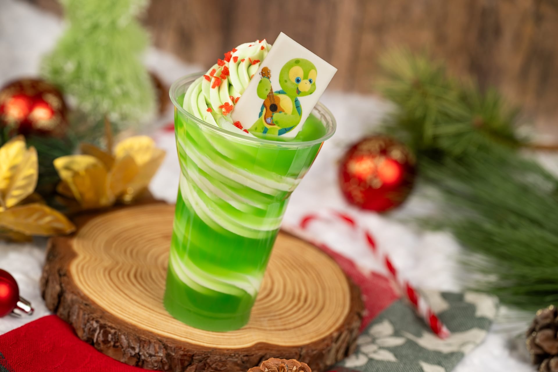A cup of green and white soft serve, decorated with holiday sprinkles and a bear candy, like treats found at Disney parks. A cup of green and white soft serve, decorated with holiday sprinkles and a bear candy, like treats found at Disney parks.
