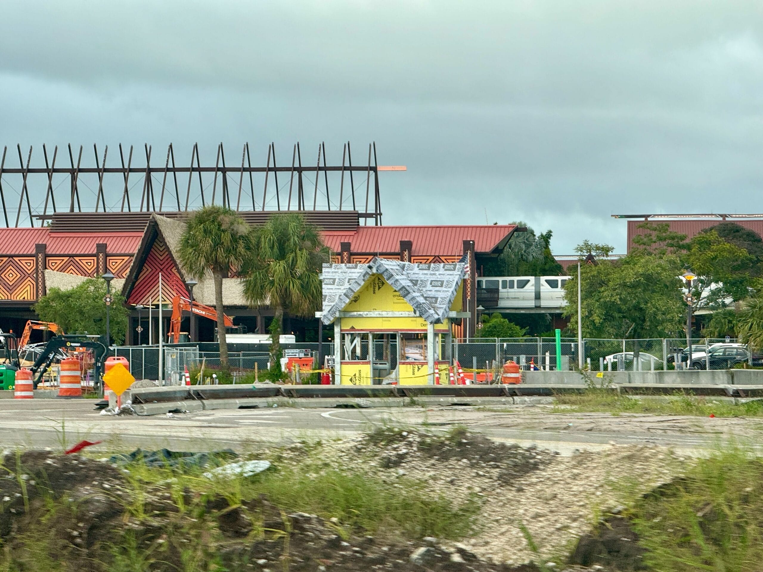A small yellow building under construction near a hotel with a monorail passing in the background. A small yellow building under construction near a hotel with a monorail passing in the background.