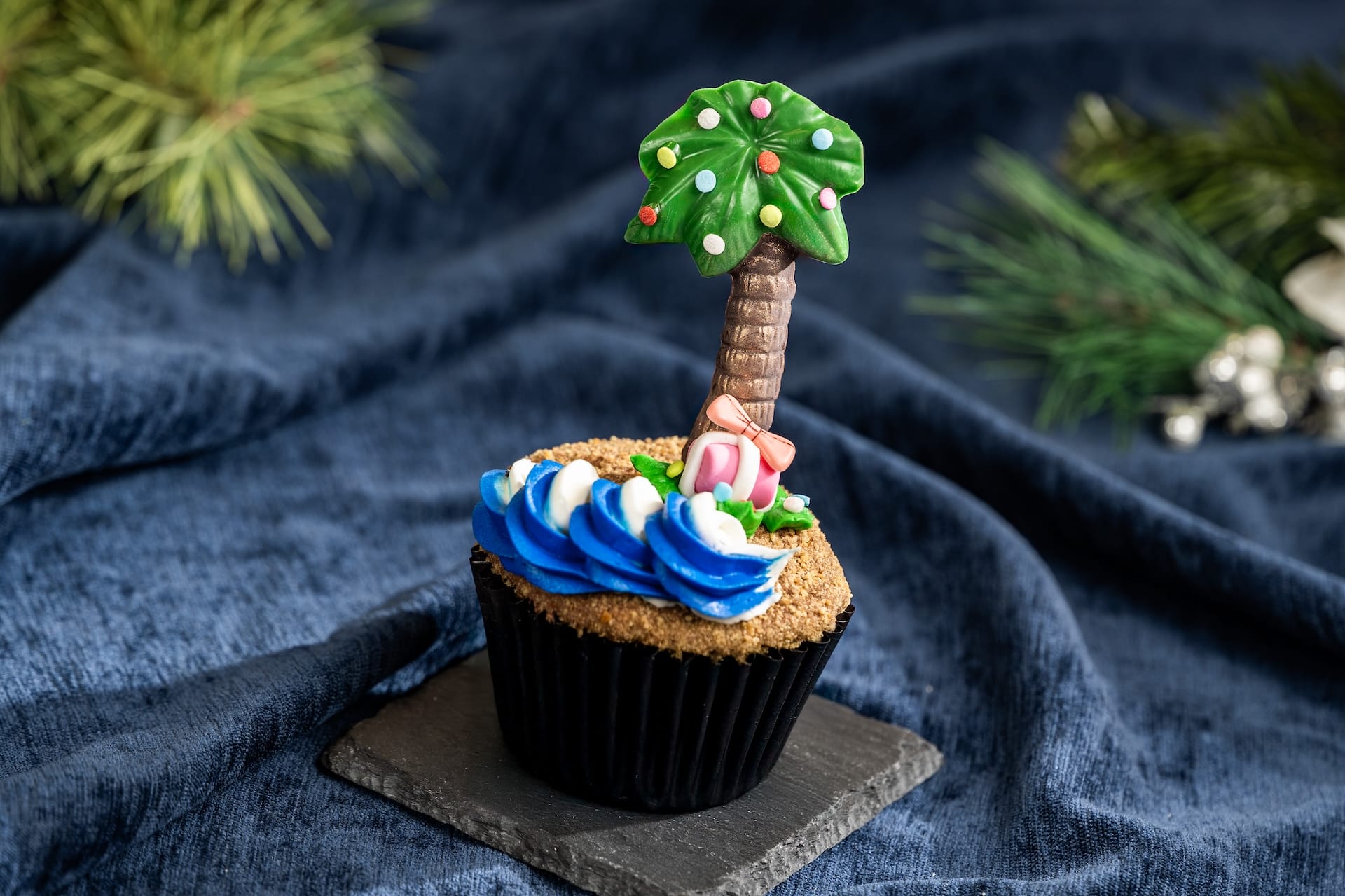 Disney Parks-inspired cupcake with blue and white frosting, sandy topping, and palm tree decor, set on dark fabric like park treats. Disney Parks-inspired cupcake with blue and white frosting, sandy topping, and palm tree decor, set on dark fabric like park treats.