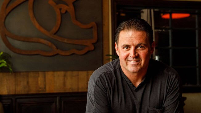 Chef James Petrakis standing at a table in his restaurant, The Polite Pig