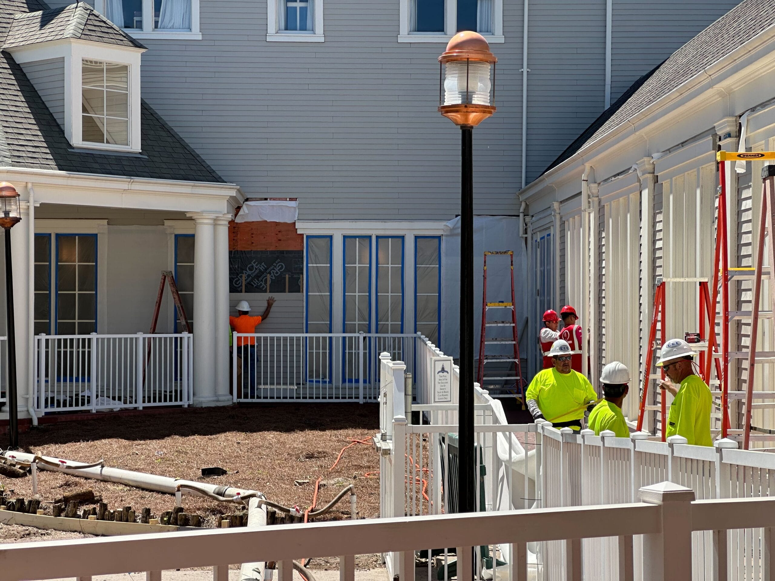 Construction workers in yellow vests and helmets were busy outside a building, surrounded by ladders and fencing. The scene unfolded under a clear sky near Disney’s Yacht Club, their work contributing to the magic of nearby attractions like Stormalong Bay Pool. Construction workers in yellow vests and helmets were busy outside a building, surrounded by ladders and fencing. The scene unfolded under a clear sky near Disney’s Yacht Club, their work contributing to the magic of nearby attractions like Stormalong Bay Pool.